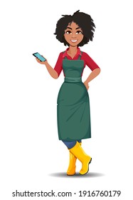 Stock vector young African American gardener woman. Beautiful lady farmer cartoon character holding smartphone