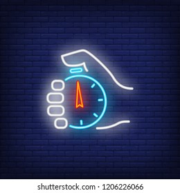 Stopwatch in hand neon sign. Glowing neon hand holding timer on dark blue brick background. Vector illustration for games, completions