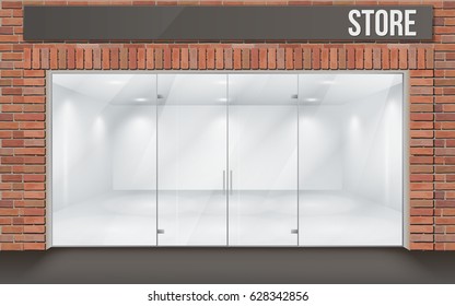 Store front with large transparent storefronts. The empty space inside is illuminated. Interior with white walls. Facade of red brick. Entrance through the large glass door.