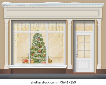 The storefront  with a door and a large window. Christmas showcase decorated with a xmas tree, glowing garland, snowflakes and gift boxes.