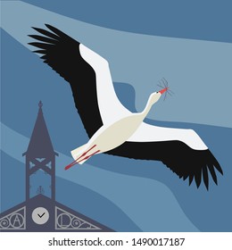 Stork flying over a blue sky and carrying sticks for its nest