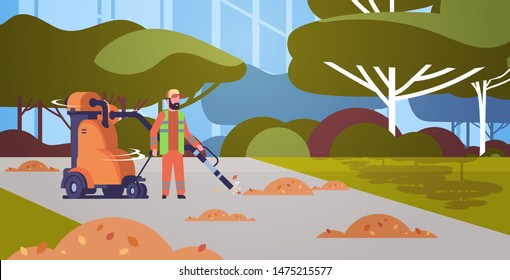 street janitor using industrial vacuum cleaner man in uniform vacuuming garbage in public park streets cleaning service concept cityscape background full length horizontal