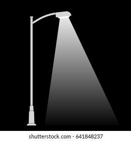 Streetlight lamp post on dark background with spotlight beam. Simple black and white vector illustration.