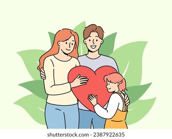 Strong family of loving parents and little pre-teen girl hold big heart. Happy spouses hug celebrating family day and rejoicing that they have become mother and father for child from orphanage.