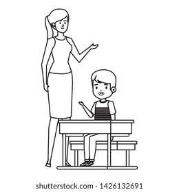 student boy seated in school desk with female teacher