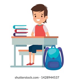student boy seated in school desk with books and bag
