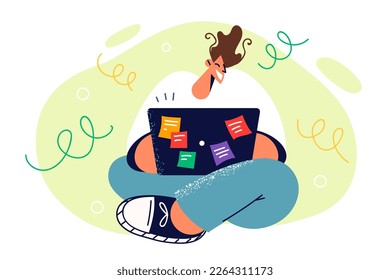 Student sits cross-legged with laptop on knees and smiles typing text of thesis for college admission. University student doing extracurricular work looking for information on internet