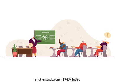 Students at physics lesson in classroom. Female teacher explaining and pointing at blackboard, pupils sitting at desks, black girl raising hand to answer. School, university, education concept