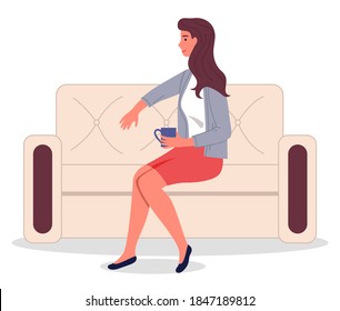 Stylish confident woman holding cup with drink, coffee or tea. Female sitting at beige sofa, leaning at back. Brunette lady smiling, wearing cardigan and skirt. Adult woman relaxing at stylish couch
