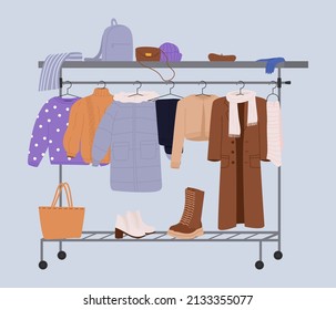 Stylish fashion clothes hanging on hangers on garment rack or rail. Fashion clothes and accessories on hanger rail. Fall, winter garments, footwear and bags. Women capsule wardrobe on racks.