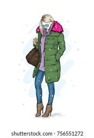 Stylish girl in a trendy winter coat, boots and with a bag. Vector illustration. Fashion skatech. Clothes and accessories.