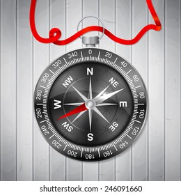 Stylish realistic compass in dark colors with wind rose, red ribbon on a wooden background. Vector illustration.