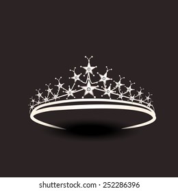 Stylish silver tiara isolated on dark brown background.