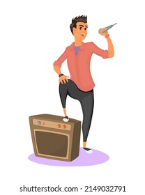 Stylish teenager holds microphone in his hand and performs song. Young man stands with one foot on amplifier