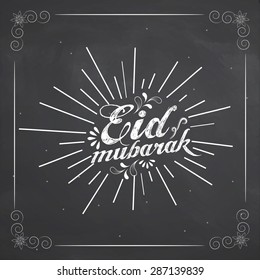 Stylish text Eid Mubarak created by white chalk on blackboard background for muslim community festival celebration.