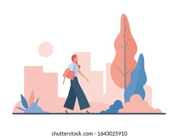 Stylish woman commuting to work. Trendy lady in formal wear and with bag walking along path near trees and bushes in park while commuting to work early in morning in modern city