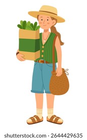 Stylish young woman in a straw hat and summer outfit holding a paper grocery bag full of fresh greens. Wearing a green vest, denim shorts, and sandals, she also carries a woven bag