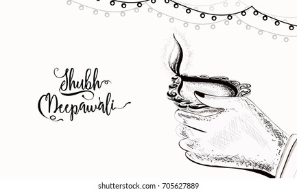 Subh Deepawali (Happy Diwali) background wtth a female hand holding illuminated oil lit lamp.