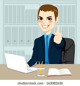 Successful businessman making thumbs up hand sign at his office while working typing on laptop on his desk 