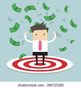 Successful businessman stand in the middle of large targets, with money blown in the sky.
