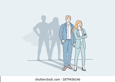 Successful cooperation and business team concept. Young man and woman business people partners standing together with big hero superman shadows on wall meaning strength of unity 