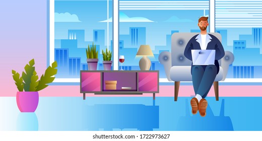 Successful freelancer in an armchair sitting with laptop. Businessman in suit working at home during quarantine. Interior background with confident young male character and large window 
