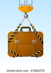 Suitcase hanging on crane hook. Lifting hook raises travel bag with slings