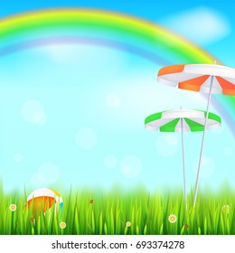 Summer background. Big bright rainbow above green field. Juicy grass, daisy flowers, ladybugs in grass on backdrop from blue sky with clouds. Landscape with Solar umbrella and inflatable ball.