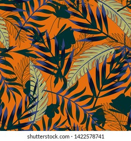 Summer bright original seamless pattern with tropical leaves and plants on an orange background. Vector design. Jung print. Floral background. Printing and textiles.