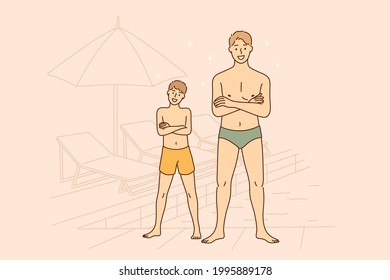 Summer day and vacations concept. Smiling happy man father and boy his son in swimming suits cartoon characters standing with folded hands on chest near pool on beach together during trip 