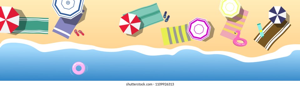 Summer holidays concept. Top view on beach with sea / ocean and pink life ring, colorful umbrellas and towels, pink inflatable flamingo flip-flops and cream for sunbathing on the sand.