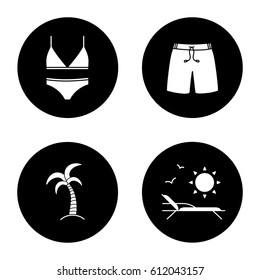 Summer icons set. Women's swimsuit, swimming trunks, palm tree, beach chair with birds and sun. Vector white silhouettes illustrations in black circles
