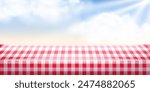 Summer or spring picnic background. Red checkered tablecloth and blue sunshine sky with clouds. Empty space food table. Tabletop advertisement backdrop