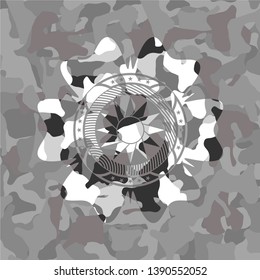 sun icon inside grey camouflaged emblem
