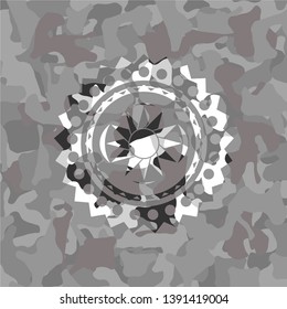 sun icon inside grey camouflaged emblem