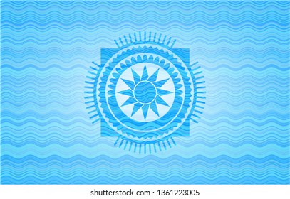 sun icon inside light blue water wave badge background.