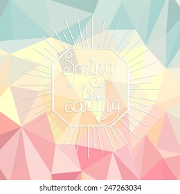 Sunburst with a calligraphical inscription of It's spring is coming on an abstract spring polygonal background.