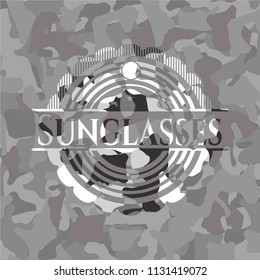 Sunglasses on grey camouflaged pattern