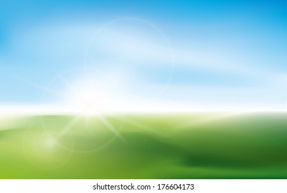 Sunny impression with blurry lens bokeh on a green field of grass with blue sky background.