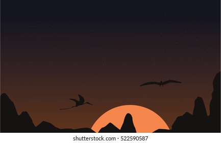 At sunset pterodactyl landscape of silhouettes