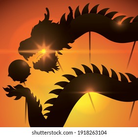 Sunset view with the silhouette of a Chinese dragon costume performing its dance chasing a 'pearl' -or ball- with poles.