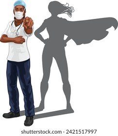 A super hero black woman doctor or nurse medical healthcare health professional in scrubs and mask PPE pointing. Revealed to be a superhero by her shadow.