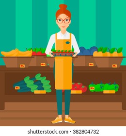 Supermarket worker with box full of apples.