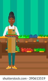 Supermarket worker with box full of apples.