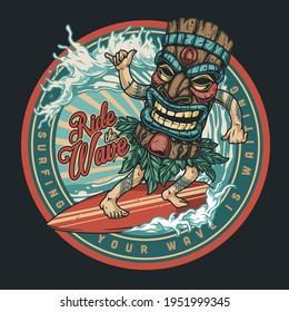 Surfing vintage round colorful label with man in big tiki wooden mask riding wave and showing shaka sign isolated vector illustration