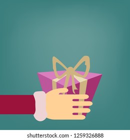 
A surprise gift box pink with a gold bow is held in his hand by a person for a holiday New Year and Christmas and Valentine's Day on a green background