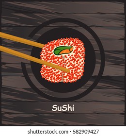 The sushi and two chopsticks on a wooden background