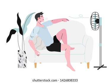 A sweaty man sitting on a sofa in front of a fan during hot summer days and not feeling well because of the terrible heat.