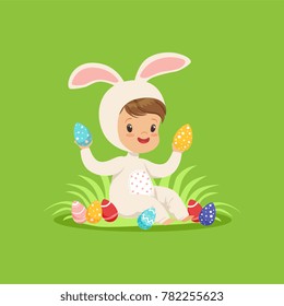 Sweet little boy in a white bunny costume sitting and playing with painted eggs, kid having fun on Easter egg hunt vector Illustration