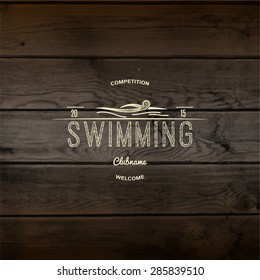 Swimming badges logos and labels for any use. On wooden background texture